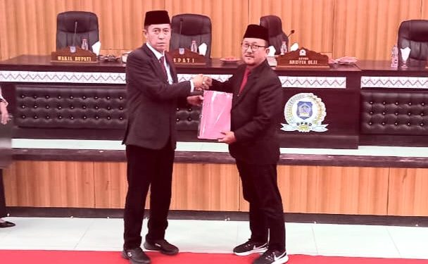 Ketua DPRD Bolsel Arifin Olii menyerahkan hasil pembahasan paripurna kepada Bupati Bolsel Iskandar Kamaru. (Foto: IST)